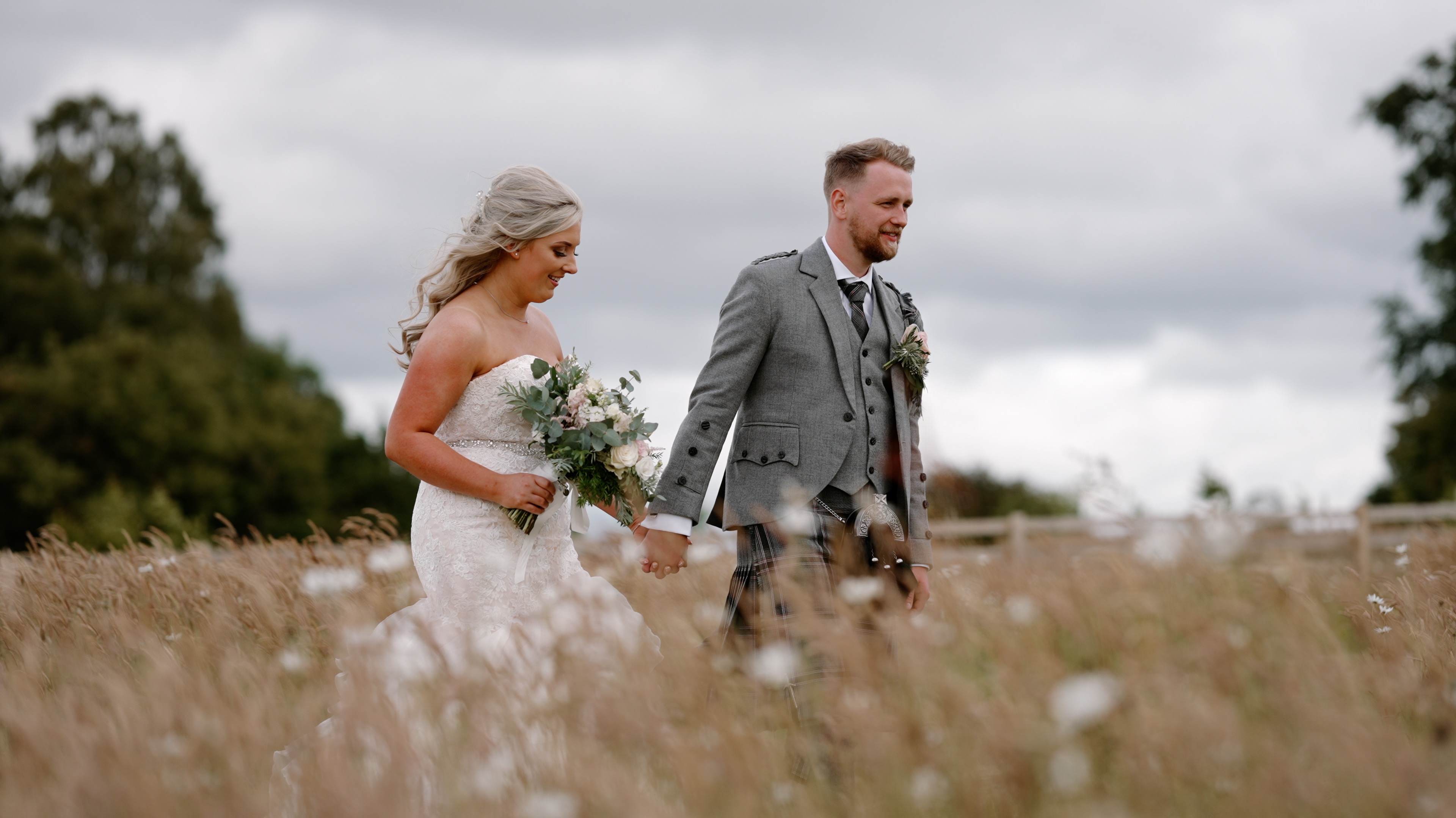 Paige and Connor, young couple walking through a field after the farm wedding